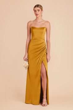 a woman in a mustard colored dress with a slited skirt and high slits