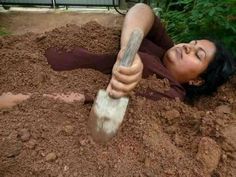 a woman laying down in the dirt with an ax sticking out of her arm and head