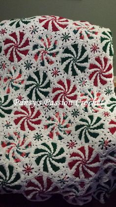 a crocheted christmas blanket with candy canes on it and a clock in the background