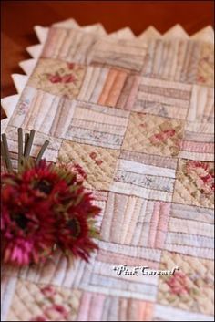 a red flower sitting on top of a table next to a piece of quilted material