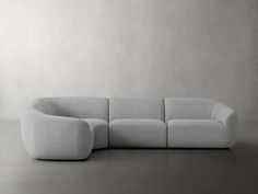 a large gray couch sitting on top of a floor next to a white wall and chair