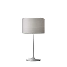 a lamp that is on top of a white table cloth with a light shade over it