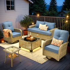 an outdoor living room with wicker furniture and blue cushions on the back deck at night