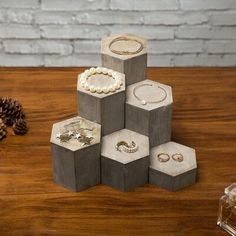 a wooden table topped with lots of jewelry next to a pine cone and other items