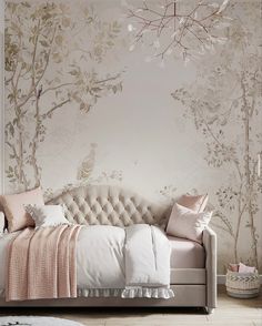 a white couch sitting in front of a wall with trees painted on it and pink pillows