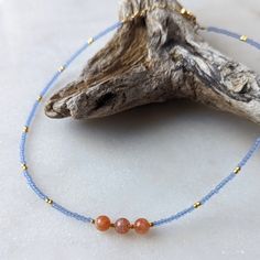 The pacific blue color of this necklace is one of my favorite trending colors. And when they are paired with Sunstone, the two colors pop in contrast. This coral and blue combination is perfect to give you all of the warm beachy vibes you could want! Sunstone is associated with the Sun's radiant energy. This is a stone that enhances your personal power and instills your life with joy, courage and optimism. This is a stone that you want close to you at all times. Colors: This beaded necklace feat Adjustable Light Blue Necklaces With Natural Stones, Everyday Blue Bohemian Beaded Necklace, Everyday Bohemian Blue Beaded Necklace, Blue Gemstone Necklace For Beach, Blue Gemstone Jewelry For The Beach, Minimalist Blue Jewelry For Beach, Minimalist Blue Necklace For Beach, Blue Natural Stones Necklace For Everyday Wear, Blue Necklaces With Natural Stones For Everyday