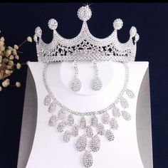 a tiara and earrings are displayed on a white display stand next to dried flowers