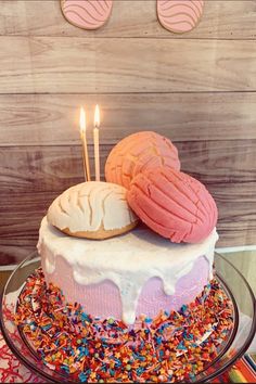 a birthday cake with sprinkles and two donuts on top that have candles sticking out of them