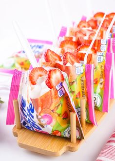 strawberries are wrapped in plastic bags and placed on a wooden tray with toothbrushes