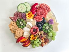 a white plate topped with lots of different types of cheeses and fruits on top of it