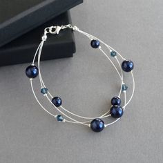 This navy floating pearl bracelet has been created using dark blue glass pearls and sparkling crystals. Its midnight blue colour makes this multi-strand bracelet an elegant gift for a bridesmaid in a navy blue themed wedding. Each three strand bracelet measures 7.5 inches / 19cm  in length and is finished with a 1 inch adjustable extension chain. This floating pearl bracelet has been completed with a silver plated lobster clasp. Your dark blue jewellery will arrive gift wrapped in the gorgeous g Blue Pearl Bracelets For Jewelry Making, Blue Pearl Jewelry For Party, Party Pearl Jewelry In Blue, Elegant Adjustable Blue Pearl Bracelet, Elegant Blue Adjustable Pearl Bracelet, Adjustable Blue Pearl Bracelet For Wedding, Blue Round Beads Bracelet For Wedding, Blue Beaded Bracelets For Weddings, Blue Round Bead Bracelets For Weddings