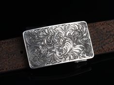 One of our most popular buckles, this understated piece by Comstock Heritage is perfect for those just starting their buckle collections, or for more formal occasions. It’s made from heavy-gauge, hand-engraved Sterling silver, and its rectangular face is adorned with beautiful, delicate scrollwork. This buckle can be paired easily blue jeans or be worn with dressier slacks. This buckle comes in two sizes as well. First smaller size measures approx. 1 5/8" x 2 5/8" and fits all 1.25" belt traps S Antique Engraved Belt Buckles For Formal Wear, Western Engraved Belt Buckles For Formal Wear, Classic Concho Belt Buckles For Formal Wear, Custom Engraved Belt Buckles For Formal Occasions, Formal Engraved Belt Buckles, Luxury Engraved Silver Belt Buckles, Luxury Silver Concho Jewelry, Antique Engraved Belt Buckles For Gift, Antique Engraved Belt Buckle Gift