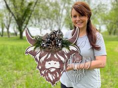 a woman holding up a cutout of a buffalo with a bow on it's head