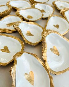 white and gold shell shaped dishes with hearts on the inside are arranged in a circle