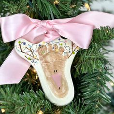 a christmas ornament with a pink bow on top of a green tree in the shape of a shoe