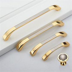 four gold door handles and knobs on a white surface