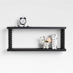 two black shelves with zebras, books and a clock on each shelf in front of a white wall