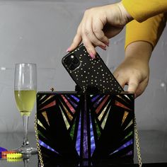 You're a work of art, so why not carry one, too? This Cyndi clutch features an Art Deco-inspired rainbow of pearlescent colors inlaid in black acrylic polished to a mirror shine. With room inside for your night-out essentials (any cell phone, keys, lipstick, and our slim Card Wallet), plus a magnetic clasp, hot pink fabric interior, and removable gold tone metal shoulder strap, this clutch is a versatile and beautiful addition to any outfit. 7.75" wide by 5.5" tall by 2.25" deep (20 cm x 14 cm x Purple Confetti, Rainbow Metal, Acrylic Clutch, Rainbow Glitter, Pink Rainbow, Square Earrings Studs, Square Stud, Black Acrylic, Black Acrylics