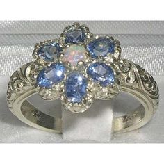 a white gold ring with blue and white stones in the center, surrounded by filigrees