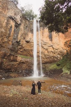 two people standing in front of a waterfall