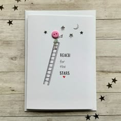 a card with a pink button on it and stars around the edge, reading reach for the stars