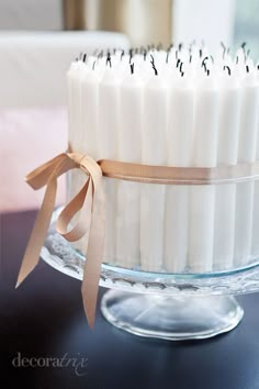 there is a cake with candles in it on the glass platter and ribbon tied around the edge