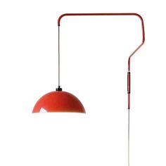 a red lamp with a long arm on a white wall next to a floor lamp