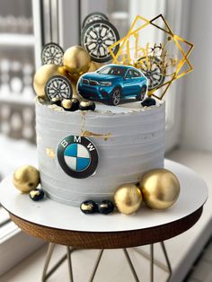 a cake decorated with gold and silver balls on a table next to a car model