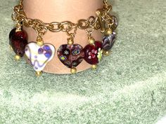 ON SALE All in wonderful SHADES of PURPLE with delightful ornamentation! Totally bright and beautiful. Absolutely one of a kind! With a total of 11 stunning, handmade MURANO, PICASSO, LAMP WORK, FOILED and MILLEFIORE HEART CHARMS and a lovely GOLD TOGGLE clasp, this great bracelet is one of a kind and absolutely unique. What a superb way to express your love to anyone in your life (it also makes a great gift to yourself). All of the hearts are in shades of PURPLE, but all are complimentary. The Heart-shaped Multicolor Charm Bracelet For Gift, Heart Shaped Multicolor Charm Bracelet For Gift, Heart-shaped Multicolor Charm Bracelet As Gift, Multicolor Heart Charm Bracelet Gift, Heart Shaped Multicolor Charm Bracelet Gift, Multicolor Double Heart Jewelry For Valentine's Day, Valentine's Day Multicolor Double Heart Jewelry, Vintage Bracelets With Heart Beads For Gift, Vintage Multicolor Jewelry For Valentine's Day