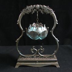 an ornate metal stand with a glass bowl hanging from it's center