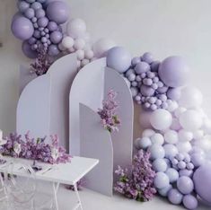 a dining room with balloons and flowers on the wall, along with a white table