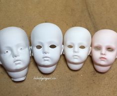 five white plastic masks are lined up in a row on the floor, with one face missing