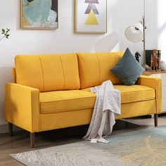 a living room with a yellow couch and paintings on the wall