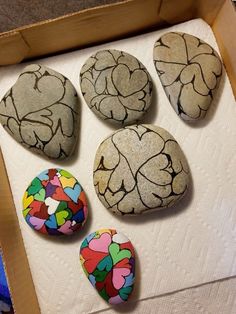 four painted rocks in a box on the floor