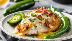 a white plate topped with chicken covered in cheese and green peppers