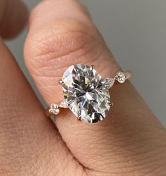 a woman's hand with a diamond ring on top of her finger and an engagement band