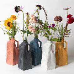 four different colored vases with flowers in them