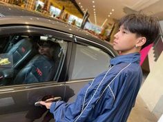 a young man holding onto the door handle of a car