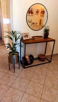 there is a mirror on the wall next to a table and potted plants in front of it