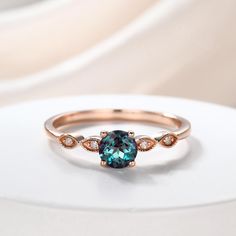 a ring with a blue stone and two white diamonds on the side, sitting on top of a table