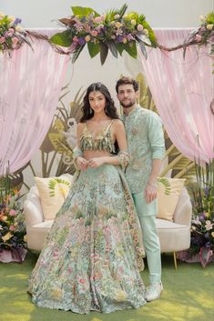 a man and woman standing next to each other in front of a floral decorated backdrop