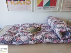 a bed with a book on top of it in front of two pictures hanging on the wall