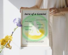 a woman holding up a framed poster with the words aura of a genni on it