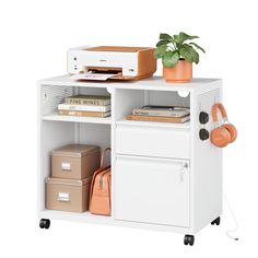 a white shelf with some books and other items on it's top, next to a plant