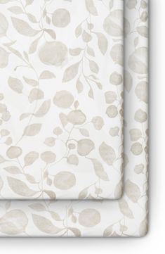 two placemats with leaves on them, one in white and the other in beige