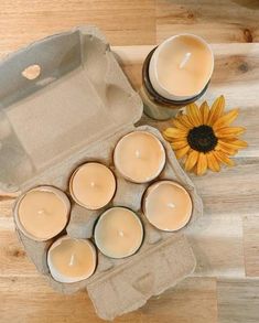 several candles are sitting in an open box next to a sunflower