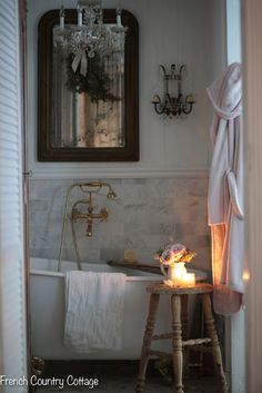 a white bath tub sitting next to a wooden table in a bathroom under a chandelier