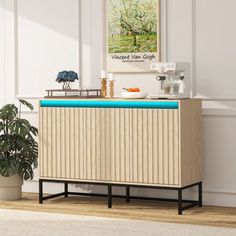 a wooden cabinet with a blue top in front of a white wall and potted plant