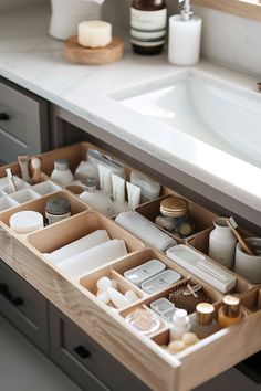 an open drawer in the middle of a bathroom counter with soaps, lotions and other items