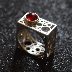 Discover the epitome of modern elegance with this handcrafted square silver ring, featuring a rich garnet centerpiece. The unique geometric design of this piece draws inspiration from contemporary architecture, offering a bold statement while maintaining a minimalist aesthetic. Each ring is meticulously crafted to highlight the natural beauty of the garnet, making it a perfect gift for those born in January or anyone who appreciates artisan jewelry. Add a touch of sophistication to any outfit with this distinctive ring. Modern Ruby Ring For Formal Occasions, Modern Red Rings For Formal Occasions, Modern Silver Ruby Ring For Formal Occasions, Modern Red Ring For Formal Occasions, Modern Garnet Rings For Anniversary, Modern Red Jewelry For Wedding, Modern Garnet Jewelry, Modern Ruby Wedding Ring, Modern Silver Ruby Ring With Polished Finish